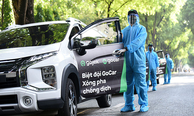 Водители стоят рядом с автомобилями GoCar, управляемыми Gojek. 