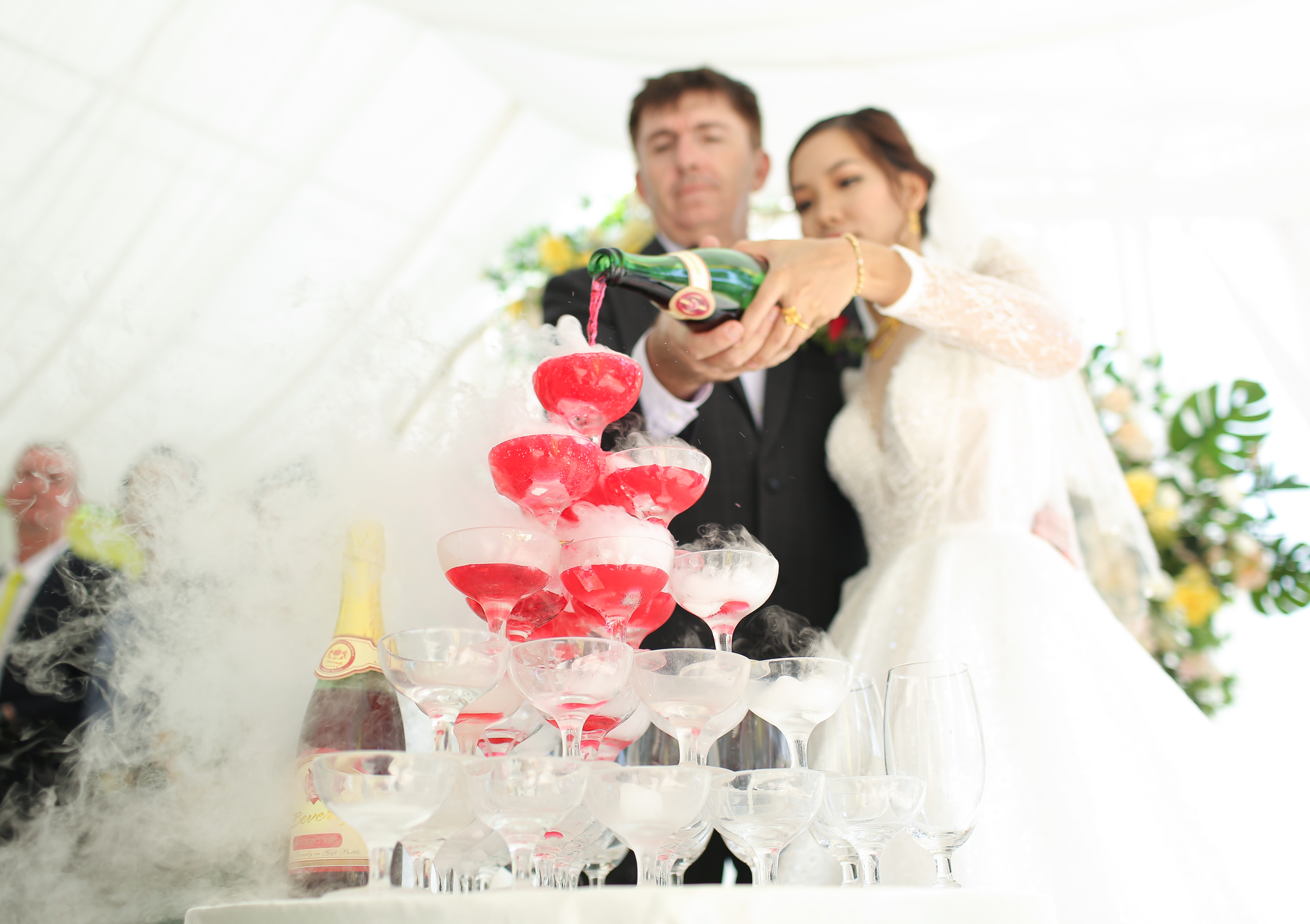 Рэй Кушерт и его жена наливают шампанское в пирамиду бокалов для вина на своей свадьбе в провинции Бинь Зыонг, Вьетнам, в апреле 2021 года. Фото любезно предоставлено Рэем Кушертом