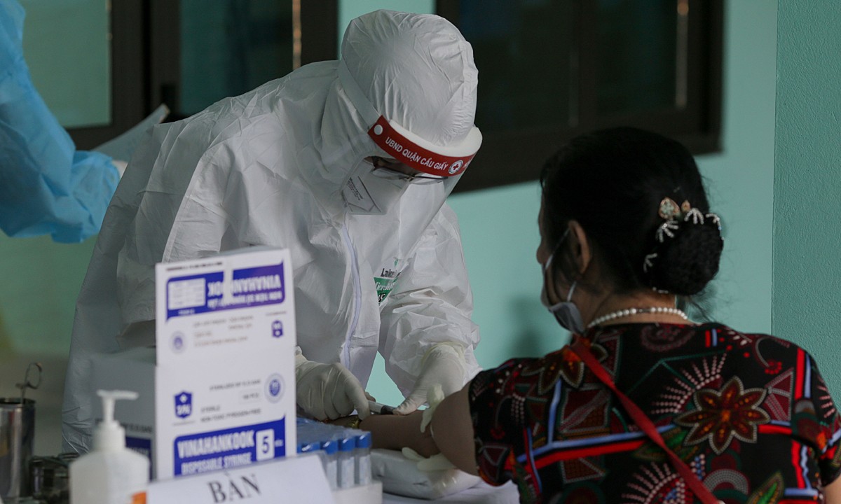 Медик берет образцы крови женщины для нового теста на коронавирус в районе Кау-Джэй в Ханое, июль 2020 года. Фото: VnExpress