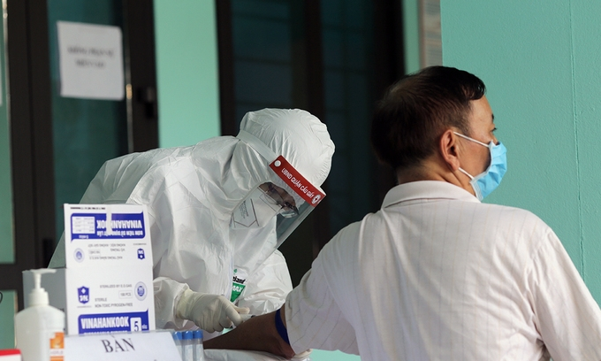 Медицинский персонал берет образцы у мужчины для проверки на новый коронавирус в Ханое. Фото: VnExpress / Tat Dinh.