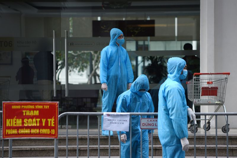 Медицинские работники в защитных костюмах стоят снаружи карантинного здания во время вспышки коронавирусной болезни (COVID-19) в Ханое, Вьетнам, 29 января 2021 года. Фото: Reuters