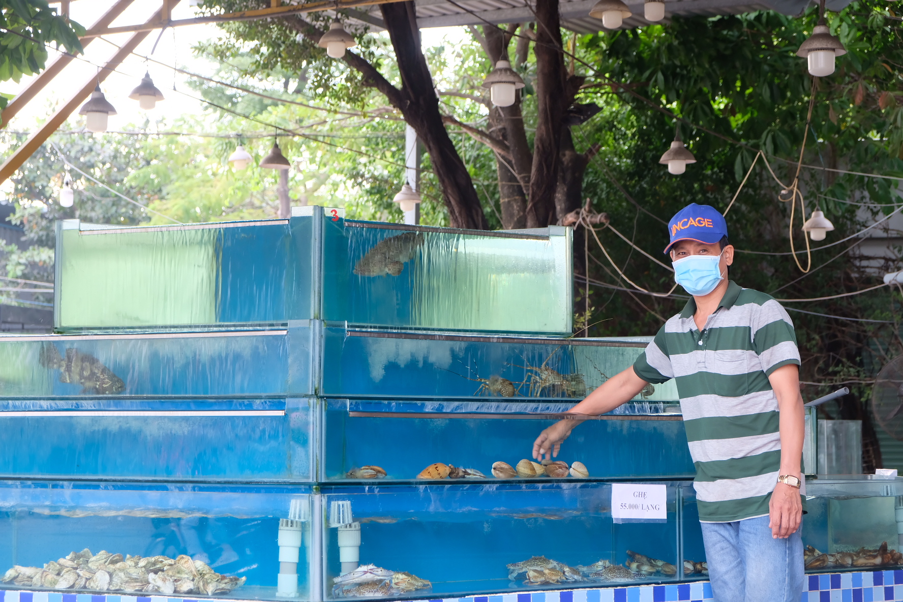 Санг, работник ресторана моллюсков в городе Тху Дык, Хошимин, возле емкости с морепродуктами, ноябрь 2021 года. Фото: Bong Mai / Tuoi Tre