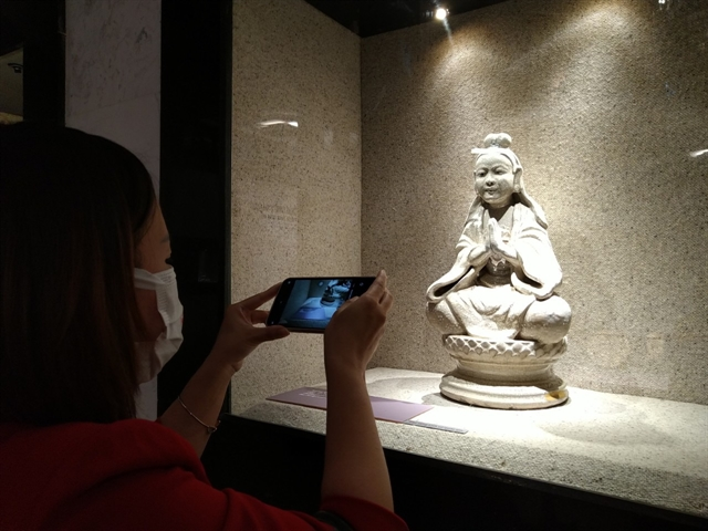 Посетитель фотографирует покрытую хрустящей глазурью статую Бодхисатвы, сделанную в Бат-Чанге в 19 веке. Фото: VNS