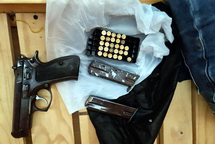 Пистолет и пули, принадлежащие банде, конфискованы офицерами на этой прилагаемой фотографии.
