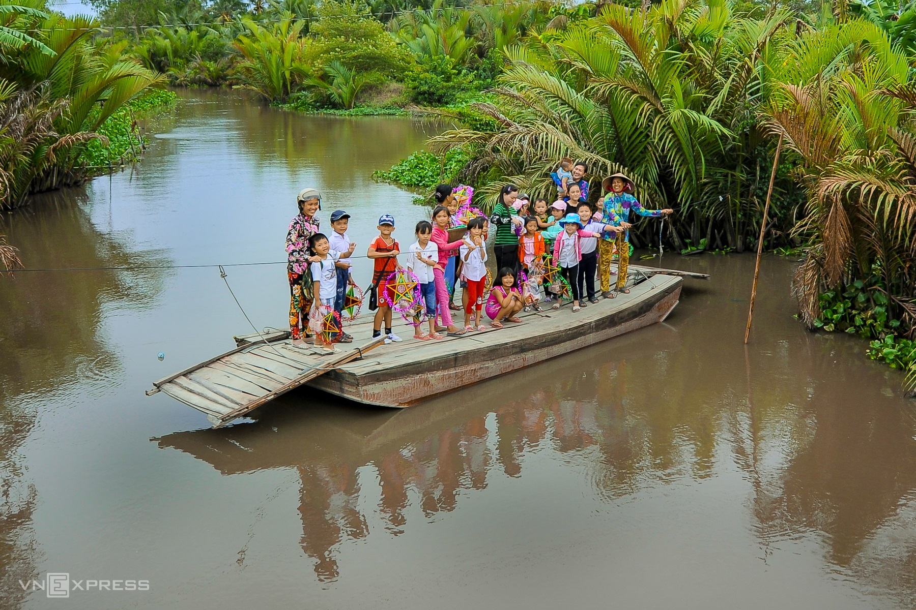 Дети переплывают реку на лодке, чтобы насладиться праздником Середины осени 2019 года в коммуне Винь Вьен, район Лонг Ми.
