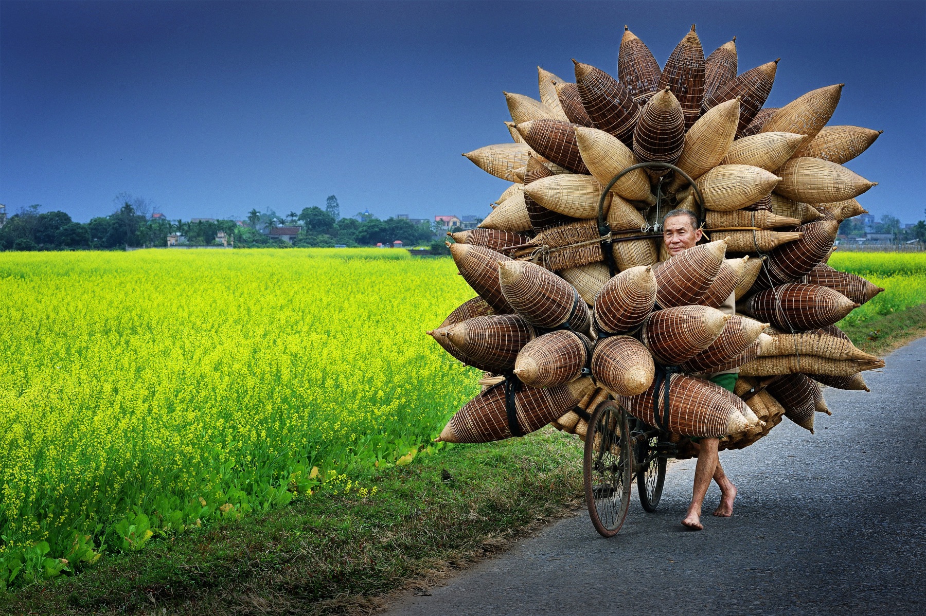 На фотографии, сделанной Ли Хоанг Лонгом, изображён мужчина, продающий бамбуковые корзины на своём велосипеде в Ханое.