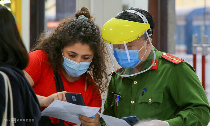 Сотрудник полиции помогает иностранке заполнить форму декларации о здравоохранении в Дананге, февраль 2021 года. Фото VnExpress/Nguyen Dong