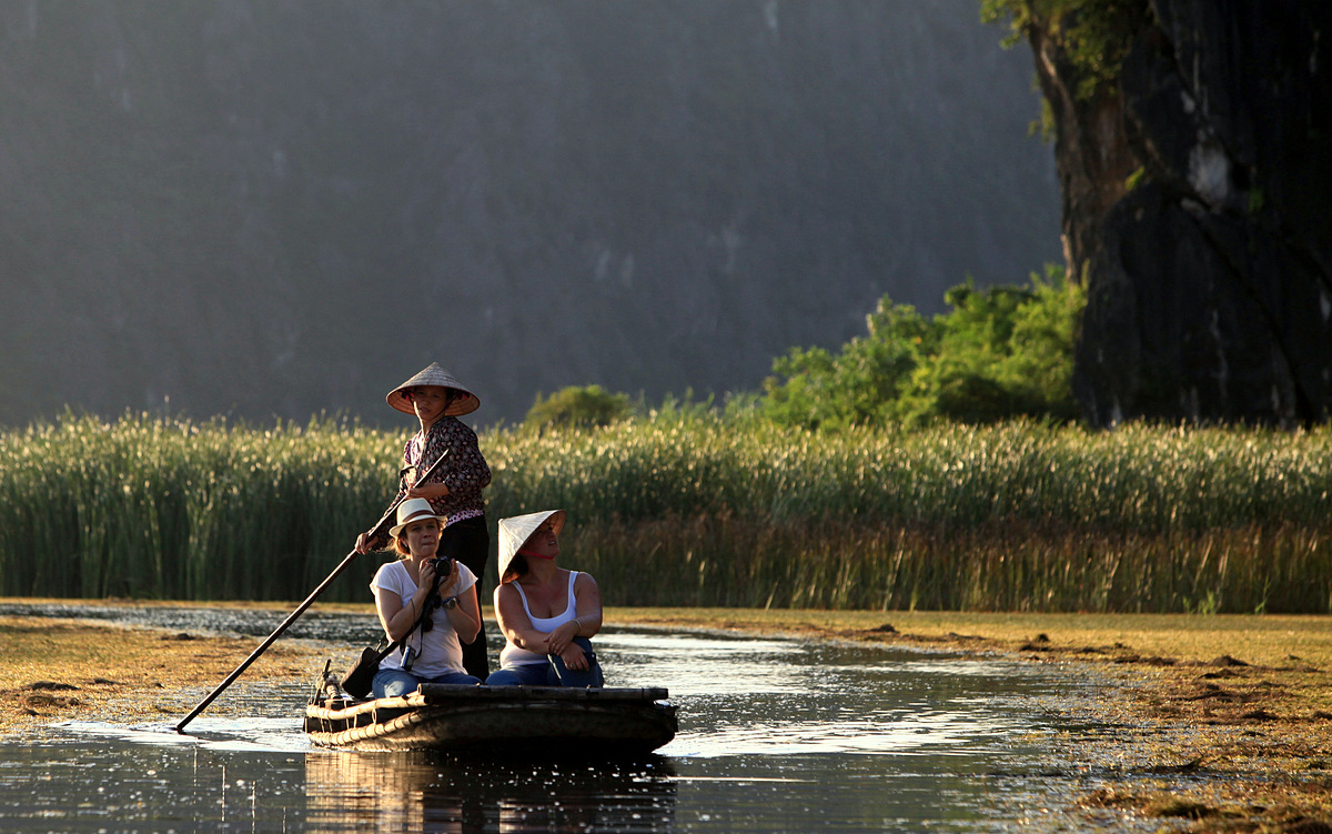 Иностранные туристы сидят на лодке, чтобы поймать находящихся под угрозой исчезновения лангуров Делакура в лагуне Ван Лонг, провинция Ниньбинь. Фото VnExpress/Le Bich