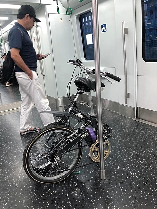 Мужчина и его компактный складной велосипед в поезде метро в Ханое в июне 2022 года. 