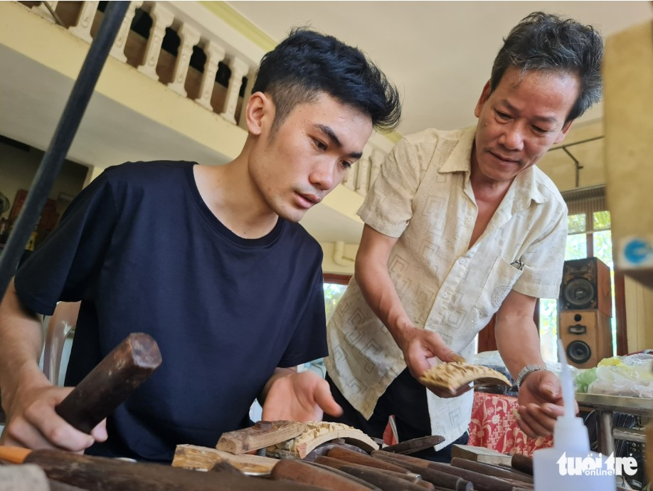 Ремесленник Доан Мин Кан (справа) учит молодого ученика вырезать бамбуковую птичью клетку. Фото: T. Mai / Tuoi Tre