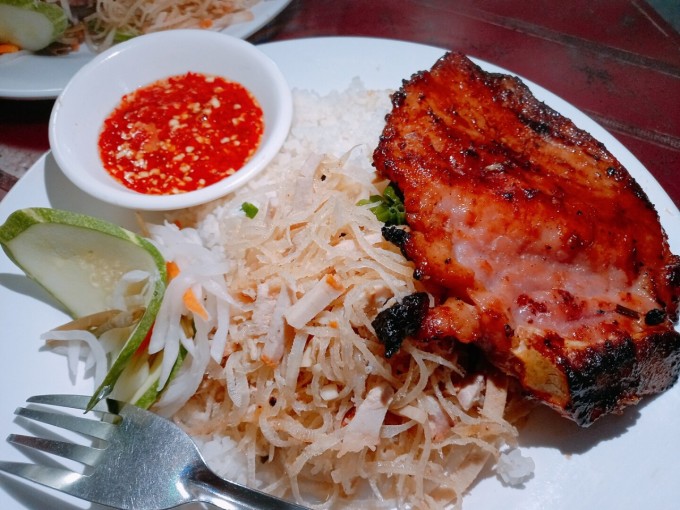 Готовая порция с ребрышками на гриле, измельченной свиной шкуркой и небольшой миской рыбного соуса чили. Фото: VnExpress/Khanh Thien