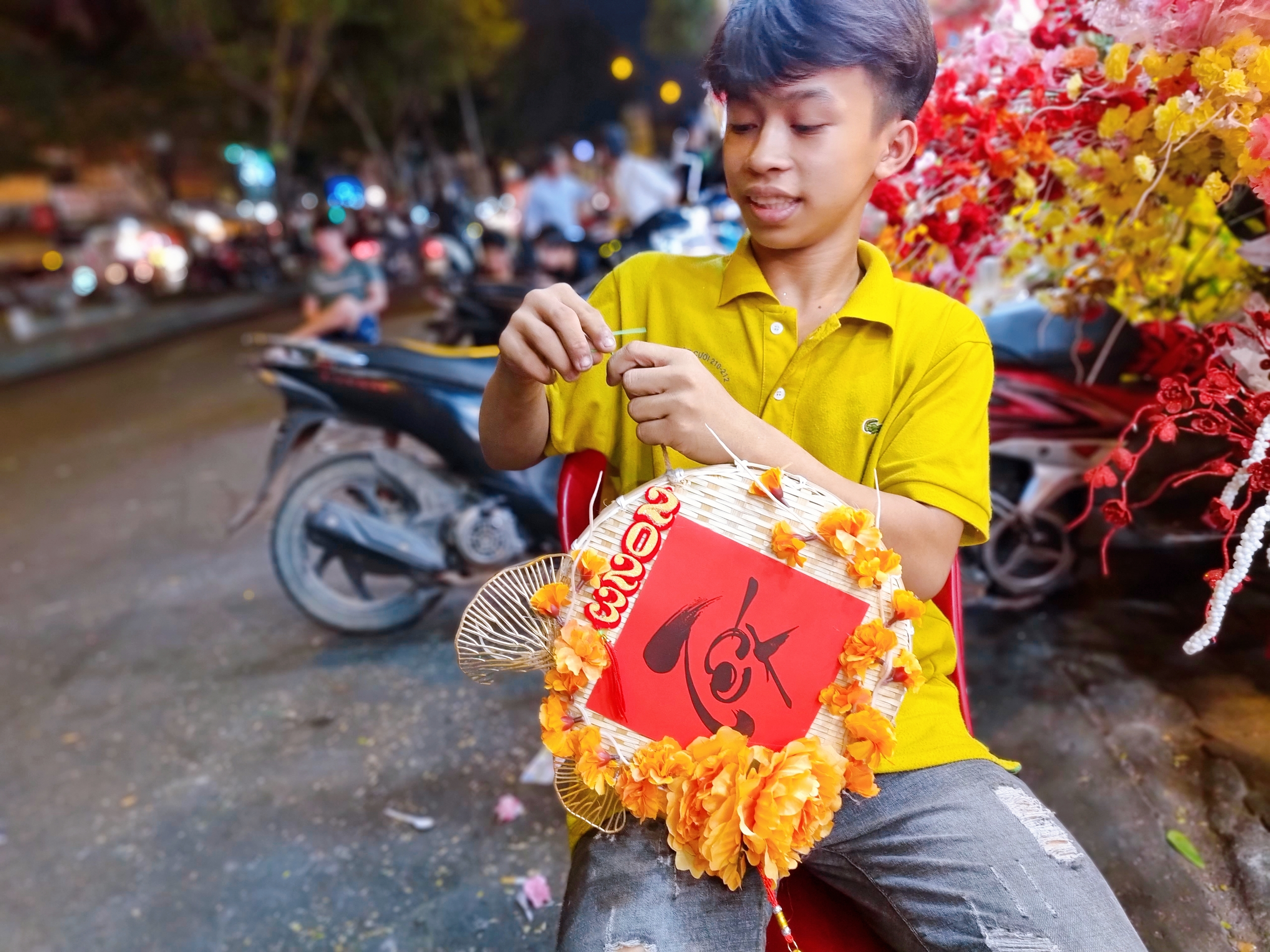Мальчик готовит украшение к празднику Тэт в магазине на улице Хай Тхыонг Лан Онг в 5-м районе Хошимина. Фото: Nhat Xuan / Tuoi Tre
